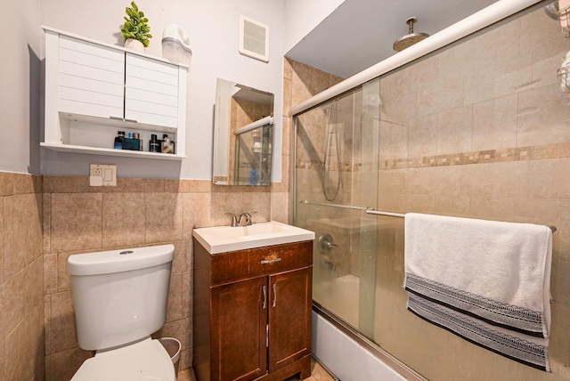 bathroom featuring tile walls, vanity, a combined bath / shower with rainfall shower, and toilet