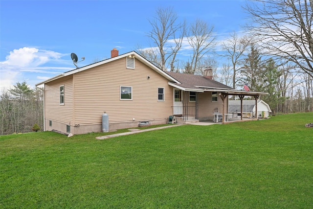 back of property featuring a chimney, a patio area, and a yard
