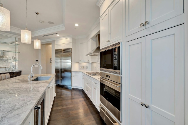 kitchen with built in appliances, wall chimney exhaust hood, ornamental molding, dark wood-style flooring, and recessed lighting
