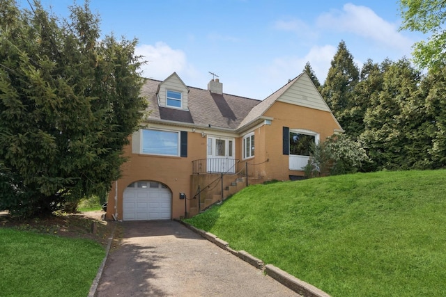 view of front facade with aphalt driveway, a chimney, roof with shingles, a front yard, and a garage