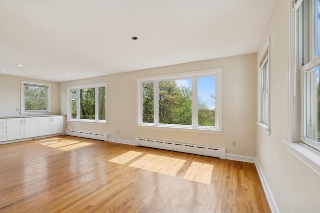 empty room featuring baseboards, recessed lighting, a baseboard heating unit, and light wood-style flooring