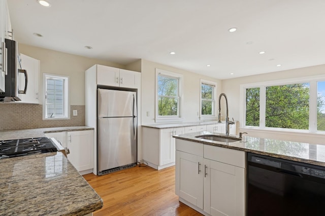kitchen featuring light stone countertops, recessed lighting, light wood-style flooring, stainless steel appliances, and a sink