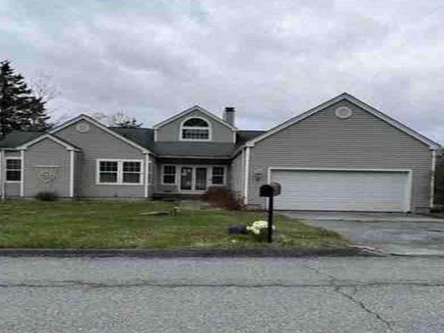 traditional home with a front lawn, an attached garage, a chimney, and concrete driveway