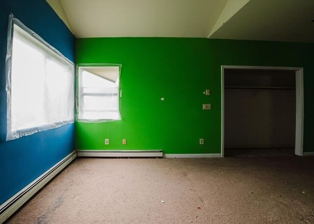 7 Cornwell St, Poughquag, NY 12570 - unfurnished bedroom featuring a baseboard heating unit, multiple windows, carpet, and vaulted ceiling