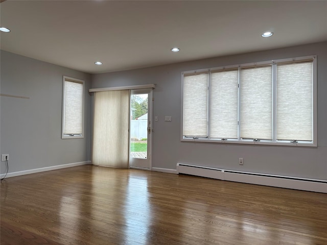 unfurnished living room with a baseboard radiator, baseboards, wood finished floors, and recessed lighting