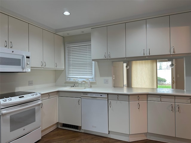 kitchen with dark wood-type flooring, a sink, white appliances, and light countertops