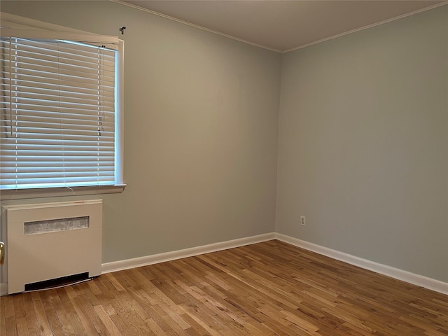 empty room with baseboards, crown molding, and hardwood / wood-style floors