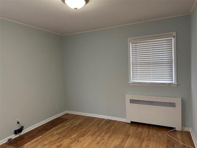 unfurnished room with hardwood / wood-style floors, baseboards, ornamental molding, and radiator