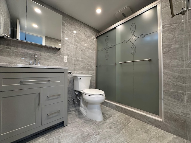 full bath featuring a shower stall, vanity, tile walls, marble finish floor, and toilet