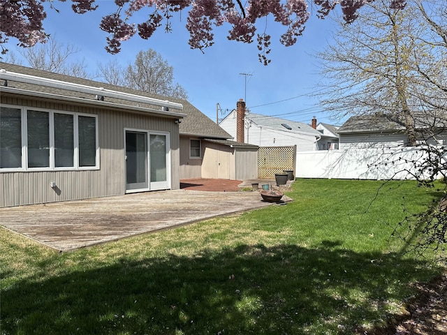 rear view of house with a yard, roof with shingles, fence, and a deck