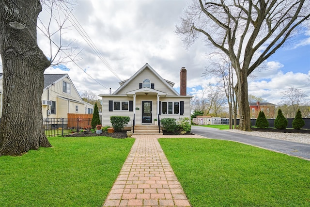 bungalow-style house featuring fence, a chimney, driveway, and a front yard