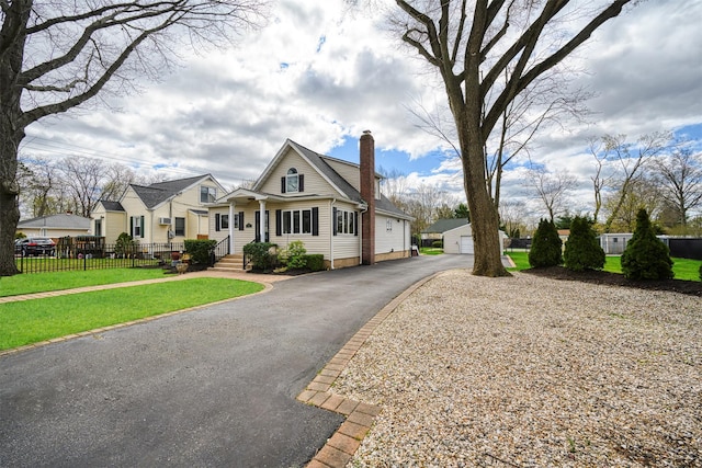 view of front of house featuring an outdoor structure, a chimney, a front yard, fence, and a garage
