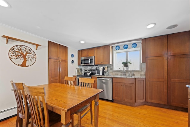 kitchen featuring appliances with stainless steel finishes, brown cabinets, light wood finished floors, and backsplash