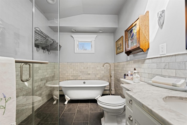 bathroom with tile walls, a freestanding bath, a shower stall, and vanity