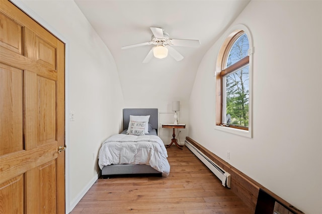 bedroom featuring lofted ceiling, ceiling fan, light wood finished floors, and a baseboard heating unit