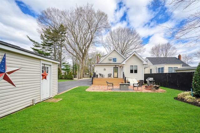back of house featuring an outdoor structure, a yard, a patio area, and fence