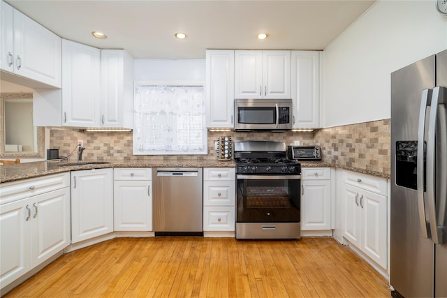 kitchen featuring appliances with stainless steel finishes, white cabinetry, and a sink