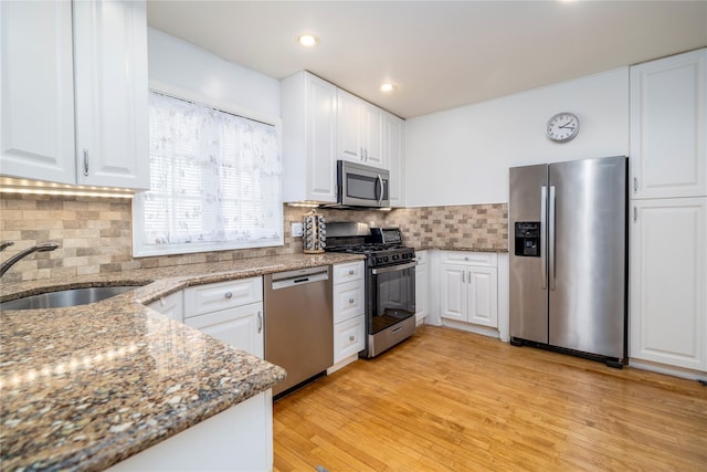 kitchen with appliances with stainless steel finishes, dark stone counters, white cabinetry, and a sink