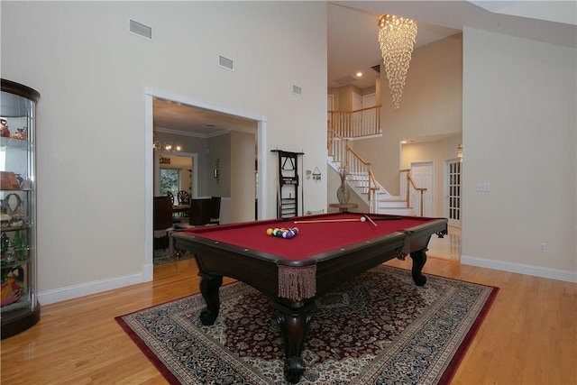 recreation room featuring visible vents, light wood-type flooring, baseboards, an inviting chandelier, and a high ceiling