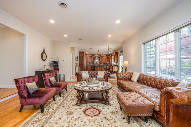 living room featuring light wood-type flooring, recessed lighting, visible vents, and ornamental molding