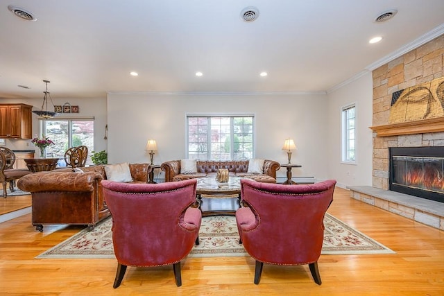 living room featuring crown molding, a stone fireplace, and a wealth of natural light