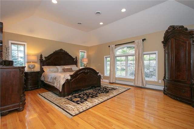 bedroom with visible vents, multiple windows, baseboard heating, and light wood finished floors