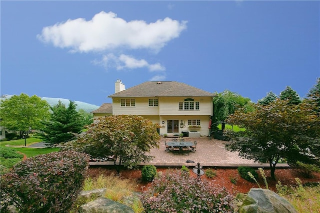 rear view of property with a wooden deck, outdoor dining area, and a chimney