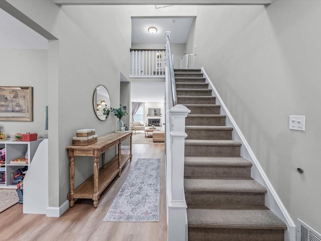 54 Hidden Ridge Dr, Syosset, NY 11791 - stairs with wood finished floors, visible vents, a towering ceiling, and baseboards