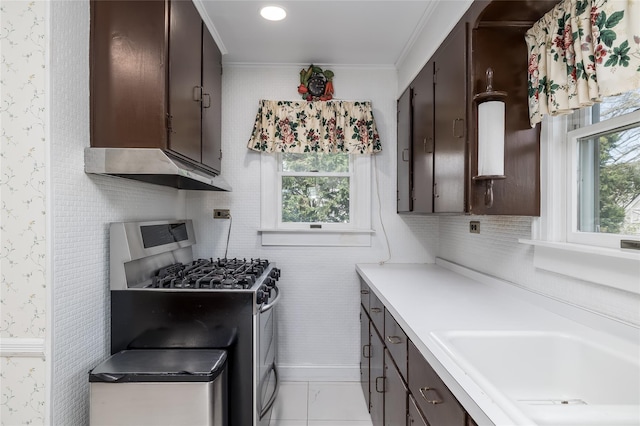 kitchen featuring stainless steel gas range, wallpapered walls, dark brown cabinetry, and a sink