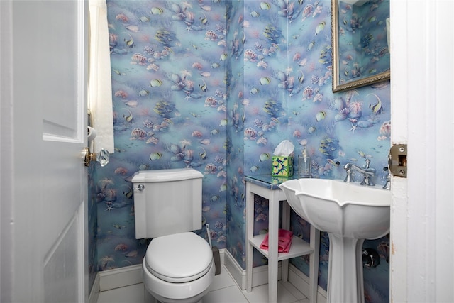 half bath featuring baseboards, tile patterned floors, toilet, and wallpapered walls