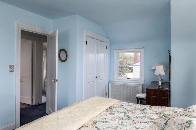 bedroom featuring radiator heating unit, lofted ceiling, and a closet