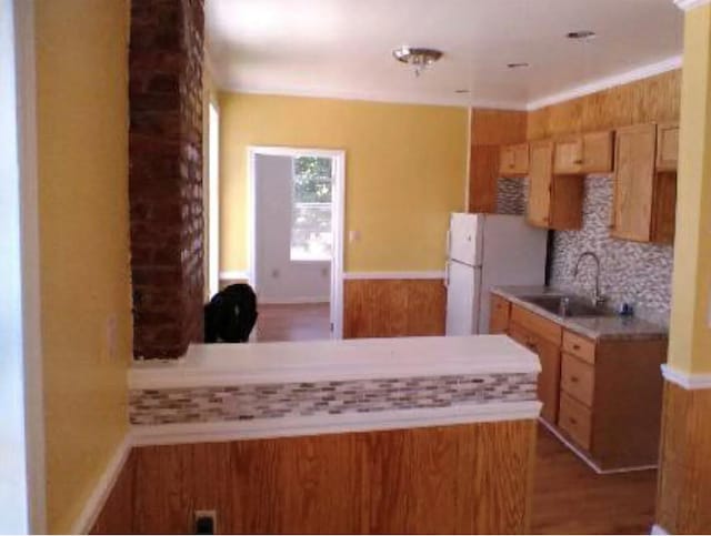kitchen featuring backsplash, light countertops, wood finished floors, a sink, and freestanding refrigerator