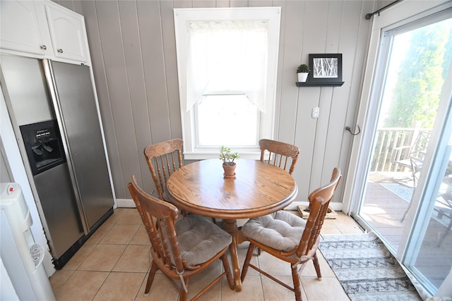dining space featuring a wealth of natural light, light tile patterned floors, and a decorative wall