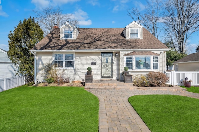 cape cod house with fence, a shingled roof, a chimney, and a front yard