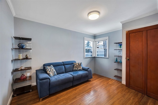 living area with wood-type flooring, baseboards, and crown molding