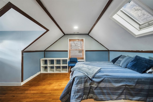 bedroom featuring lofted ceiling with skylight, wood finished floors, and baseboards