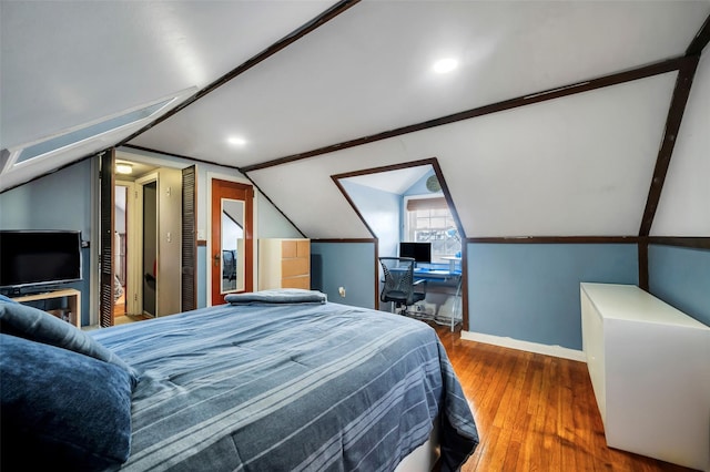 bedroom featuring wood finished floors, baseboards, and vaulted ceiling