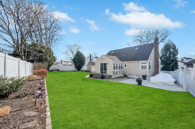 back of property featuring a patio area, a lawn, a chimney, and a fenced backyard