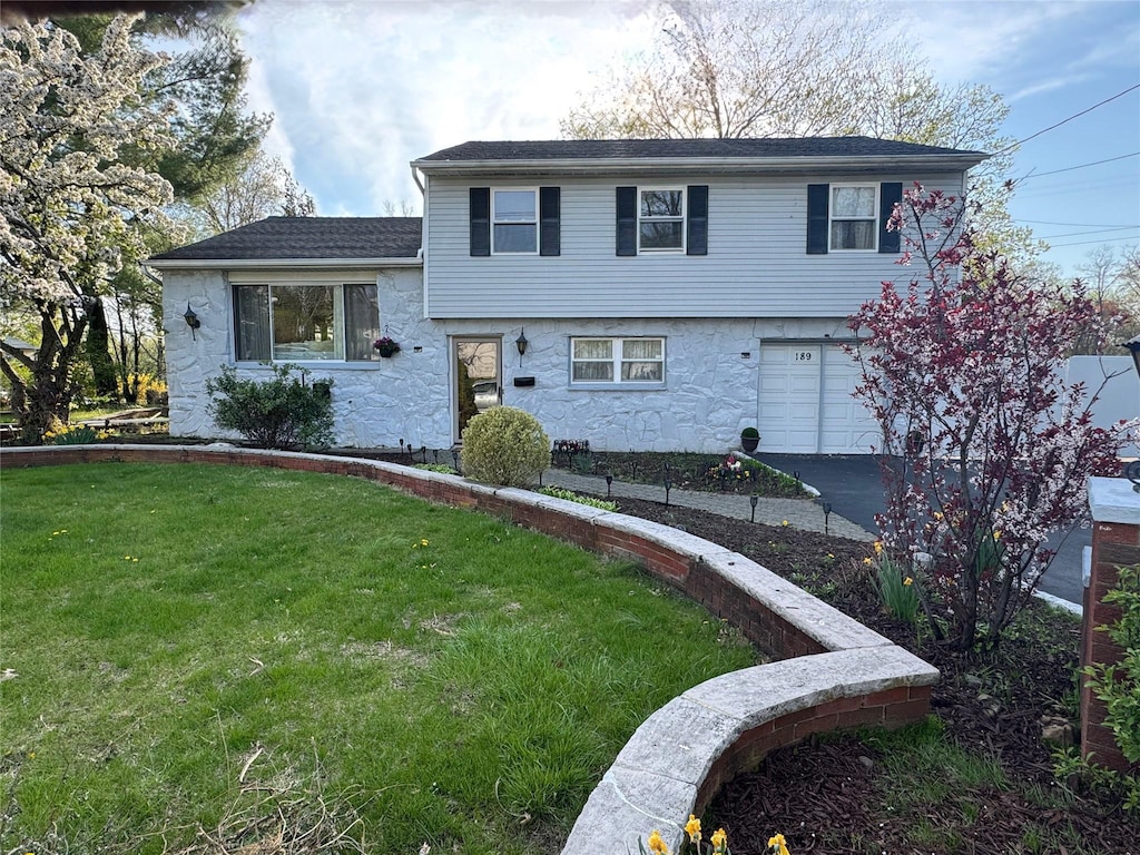tri-level home featuring driveway, a front yard, and a garage