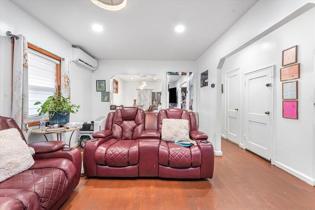 living area with recessed lighting, a wall mounted air conditioner, baseboards, and wood finished floors