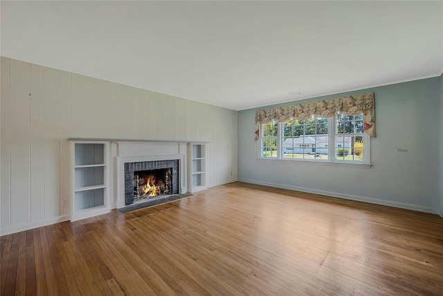 unfurnished living room featuring hardwood / wood-style floors, baseboards, and a fireplace
