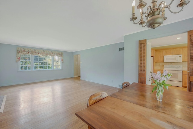 unfurnished dining area with an inviting chandelier, light wood-type flooring, visible vents, baseboards, and ornamental molding