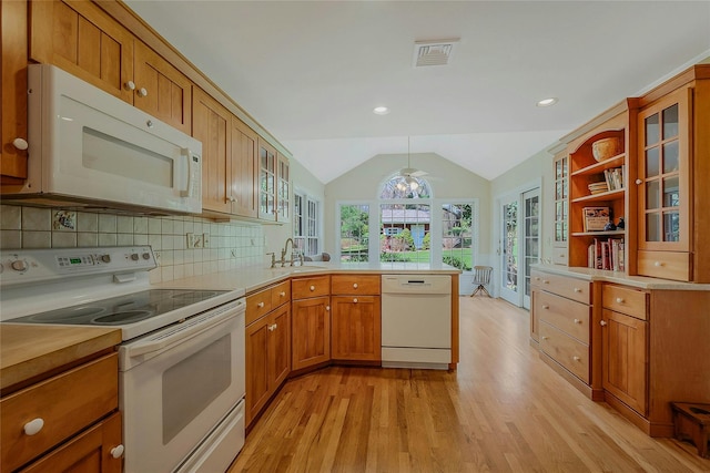 kitchen with a sink, light wood-style floors, visible vents, white appliances, and a peninsula