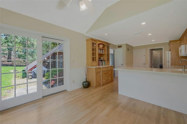 kitchen featuring a sink, white appliances, open shelves, light wood-type flooring, and light countertops