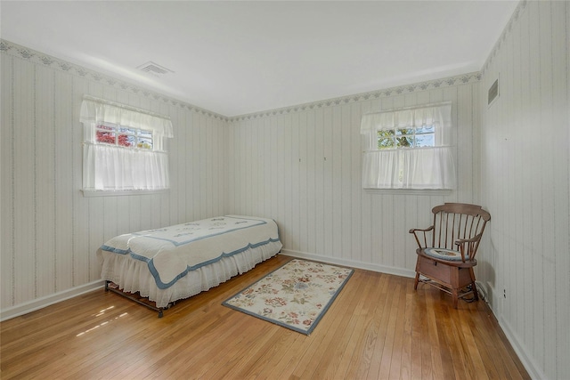 bedroom featuring multiple windows, baseboards, hardwood / wood-style flooring, and visible vents