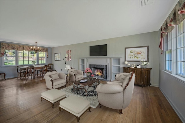 living area featuring wood finished floors, a healthy amount of sunlight, a notable chandelier, and baseboards