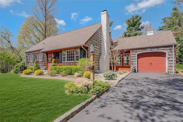 view of front facade with a chimney, driveway, roof with shingles, a front lawn, and an attached garage