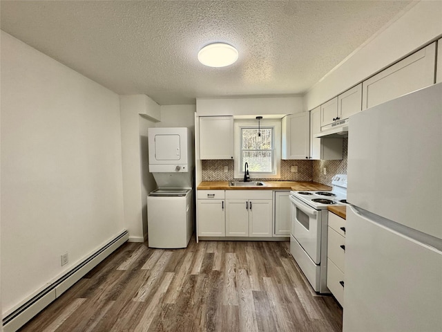 kitchen featuring baseboard heating, wooden counters, white appliances, under cabinet range hood, and stacked washer and clothes dryer