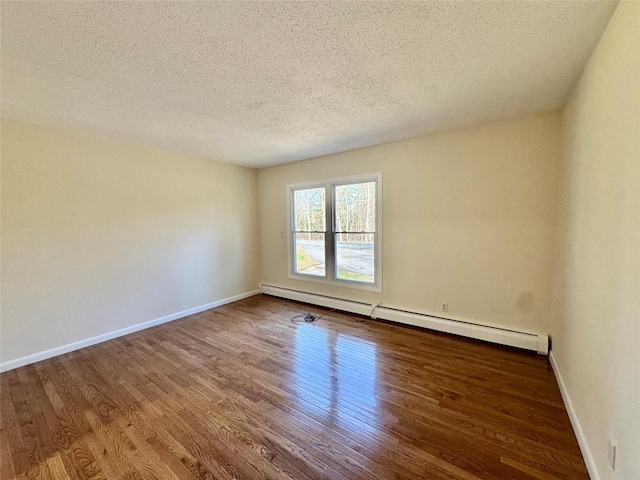 spare room with a baseboard radiator, wood finished floors, a textured ceiling, and baseboards