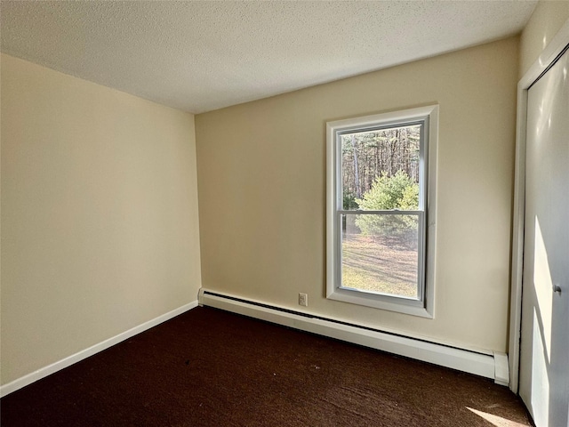 unfurnished room featuring a baseboard heating unit, dark carpet, a textured ceiling, and baseboards
